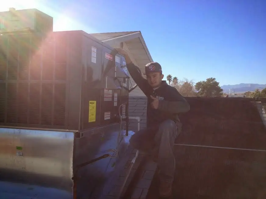 HVAC technician performing AC Tune-Up on a rooftop unit in Adams